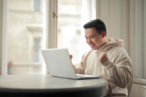 a guy is excited over online learning courses through his laptop
